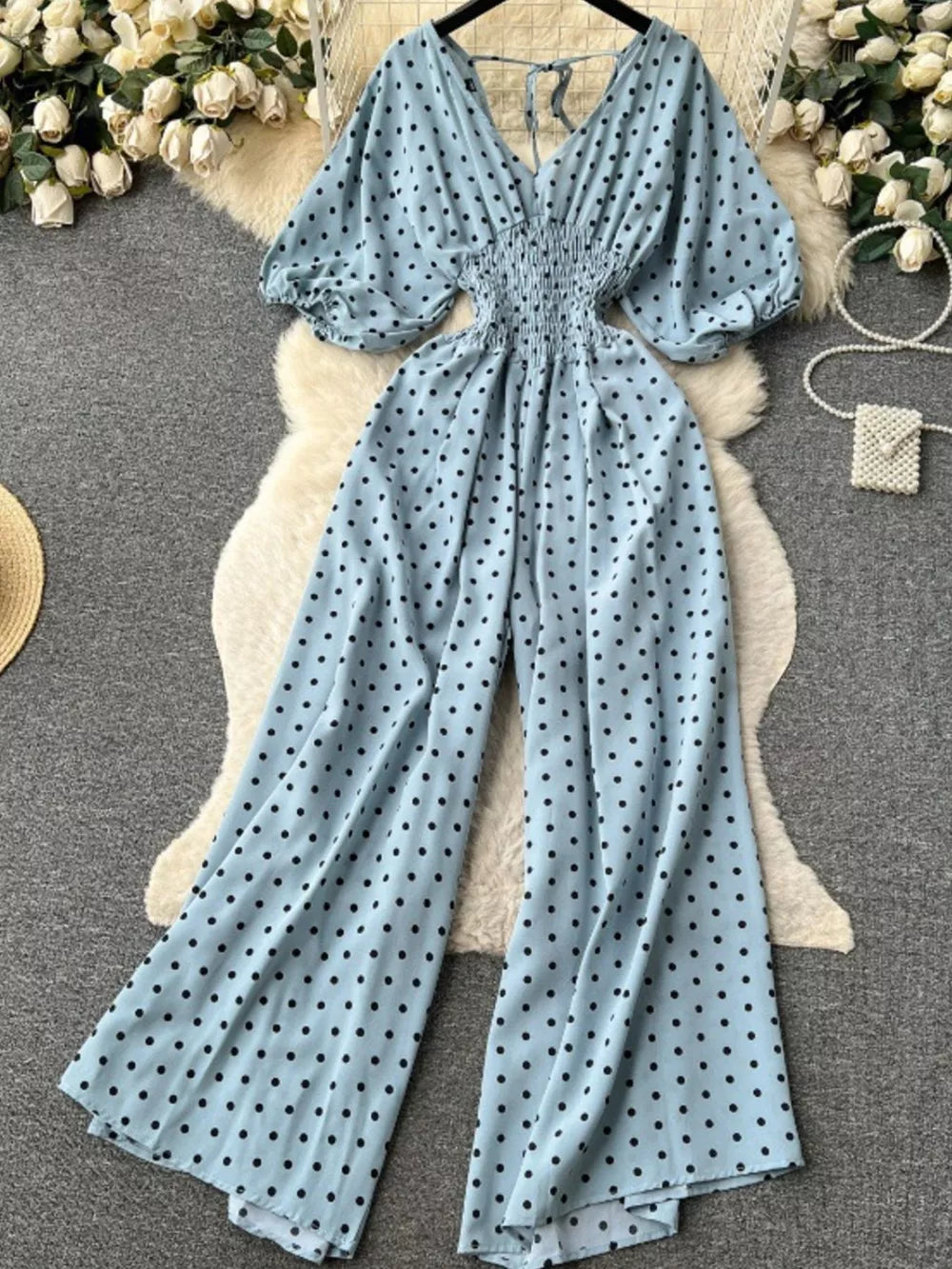 Light Blue polka dot smocked wide-leg romper with puff sleeves and tie back.