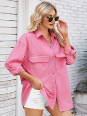 Pink oversized denim shirt with chest pockets and button front, styled with white shorts.