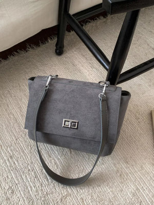 Sleek gray suede crossbody bag with flap closure and silver hardware.
