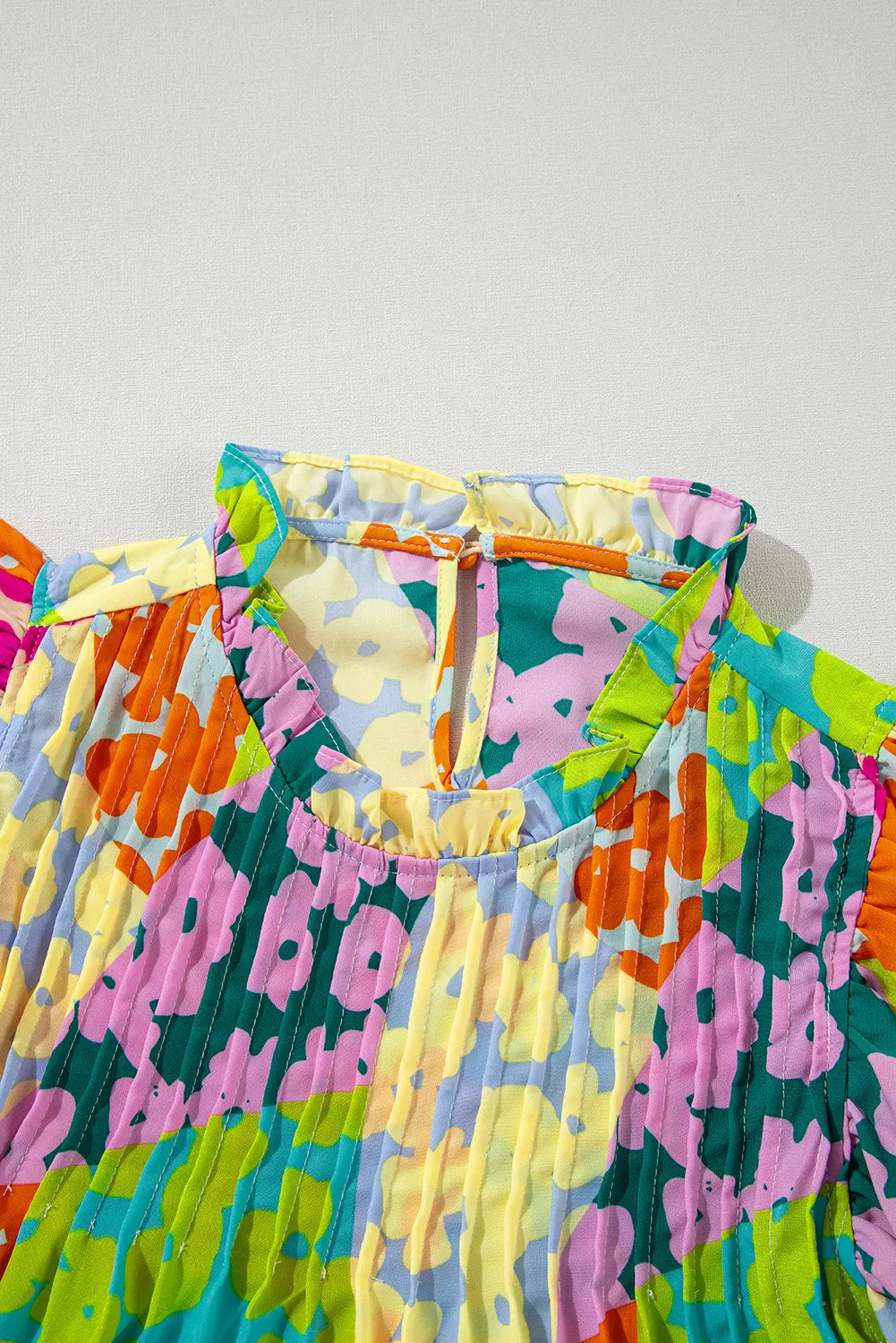 Floral ruffle yoke blouse with flutter sleeves and a mock neck.