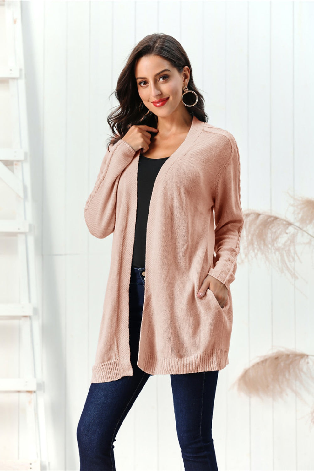 Apricot cable knit open front cardigan with pockets and braided sleeve detail.