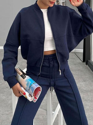 Dark blue bomber jacket and wide-leg tracksuit with white crop top.