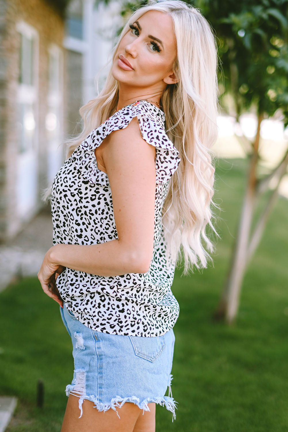 White leopard print flutter sleeve blouse with ruffled neckline.