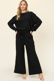 Textured black loungewear set with crewneck sweatshirt and wide leg pants with drawstring waist.