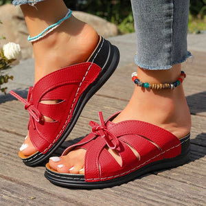 Red criss-cross wedge sandals with a bow detail and white stitching.