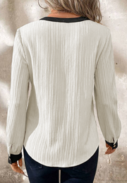 Textured white V-neck blouse with black trim and cuffs.