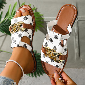 Patterned slide sandals in white with black print and gold chain accent.