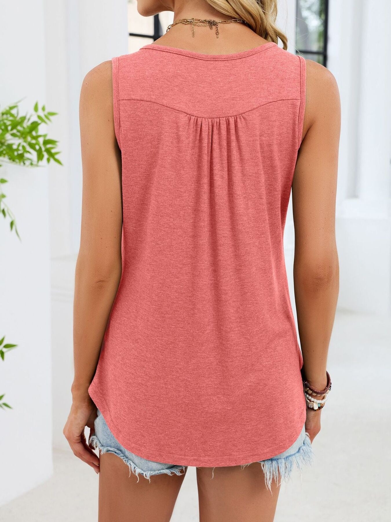 Pink ruched tank top with button detail and curved hem.