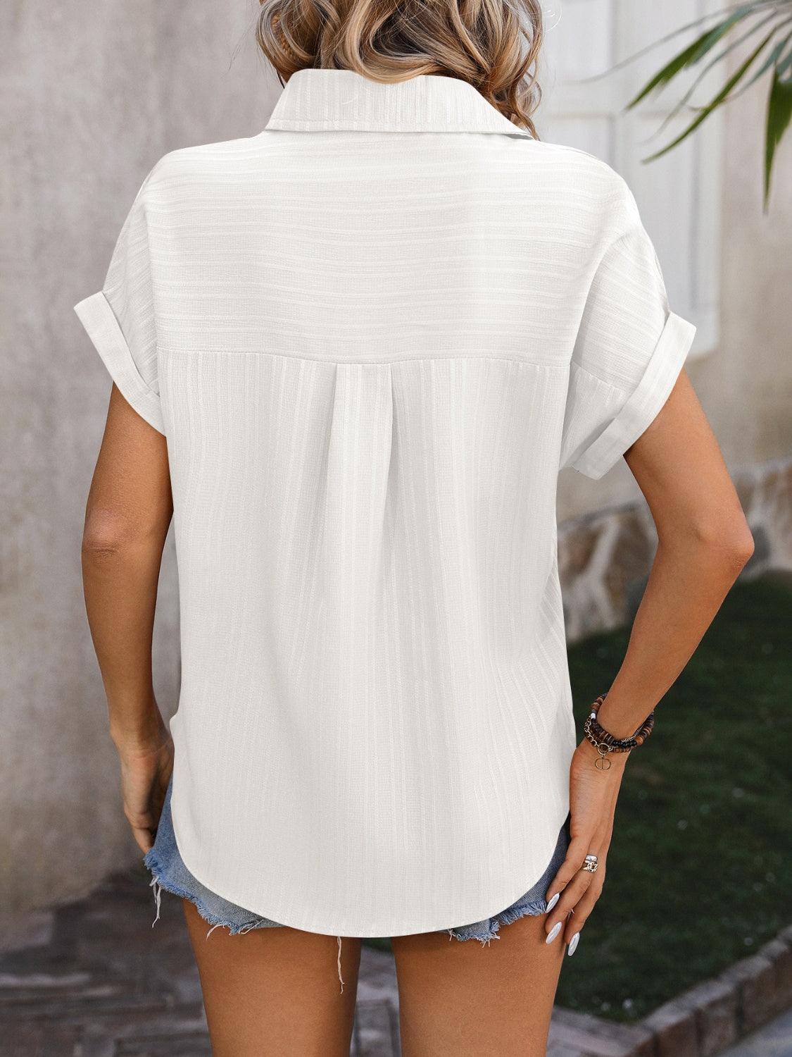 White textured button-down shirt with cuffed short sleeves and a back pleat detail.