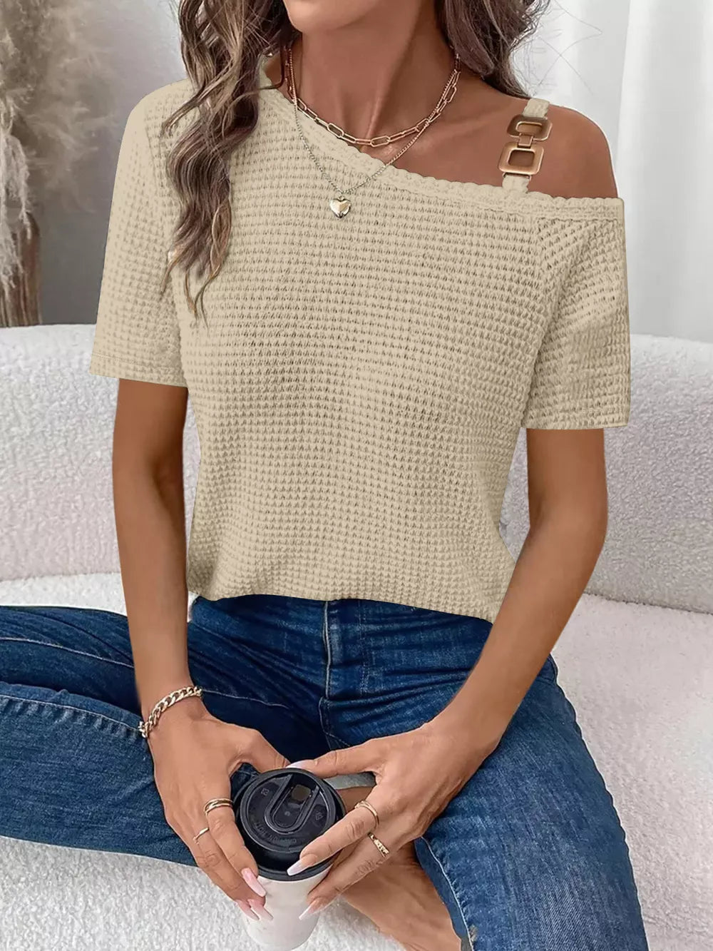 Beige waffle knit one-shoulder t-shirt with gold buckle detail on strap.