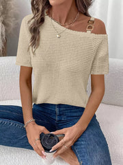 Beige waffle knit one-shoulder t-shirt with gold buckle detail on strap.