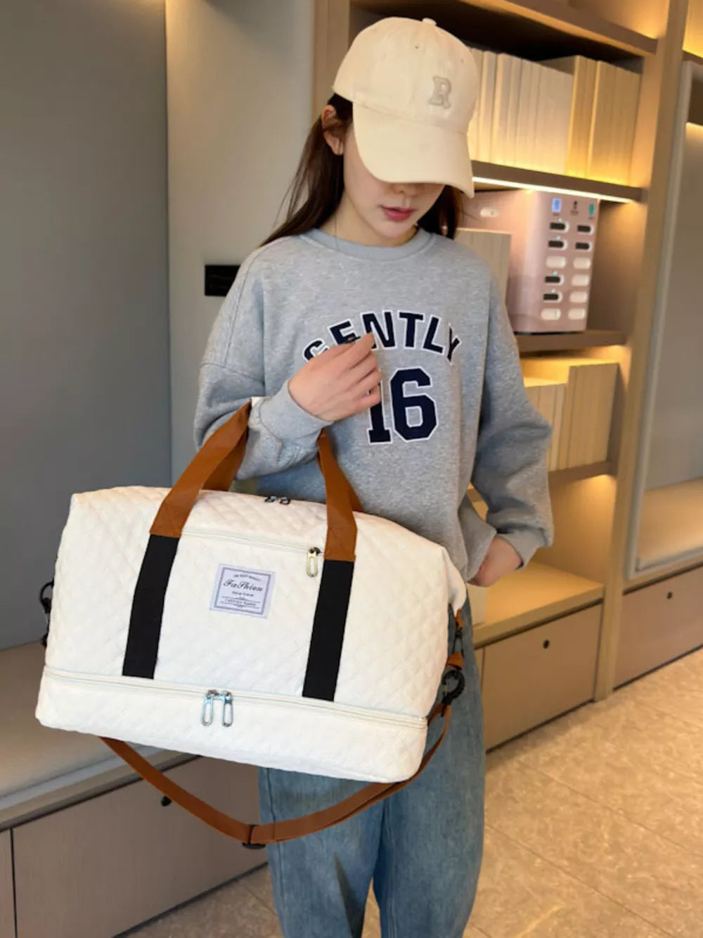 Creamy-white quilted travel duffel bag with brown handles and a detachable strap.