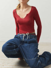 Burgundy ribbed crop top with a V-neck and raw hem, styled with baggy jeans.