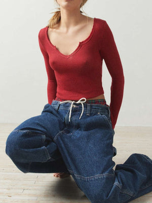 Burgundy ribbed crop top with a V-neck and raw hem, styled with baggy jeans.
