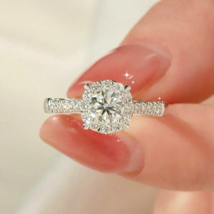 Sterling silver ring with a large round moissanite center stone and halo, accented with small stones on the band.