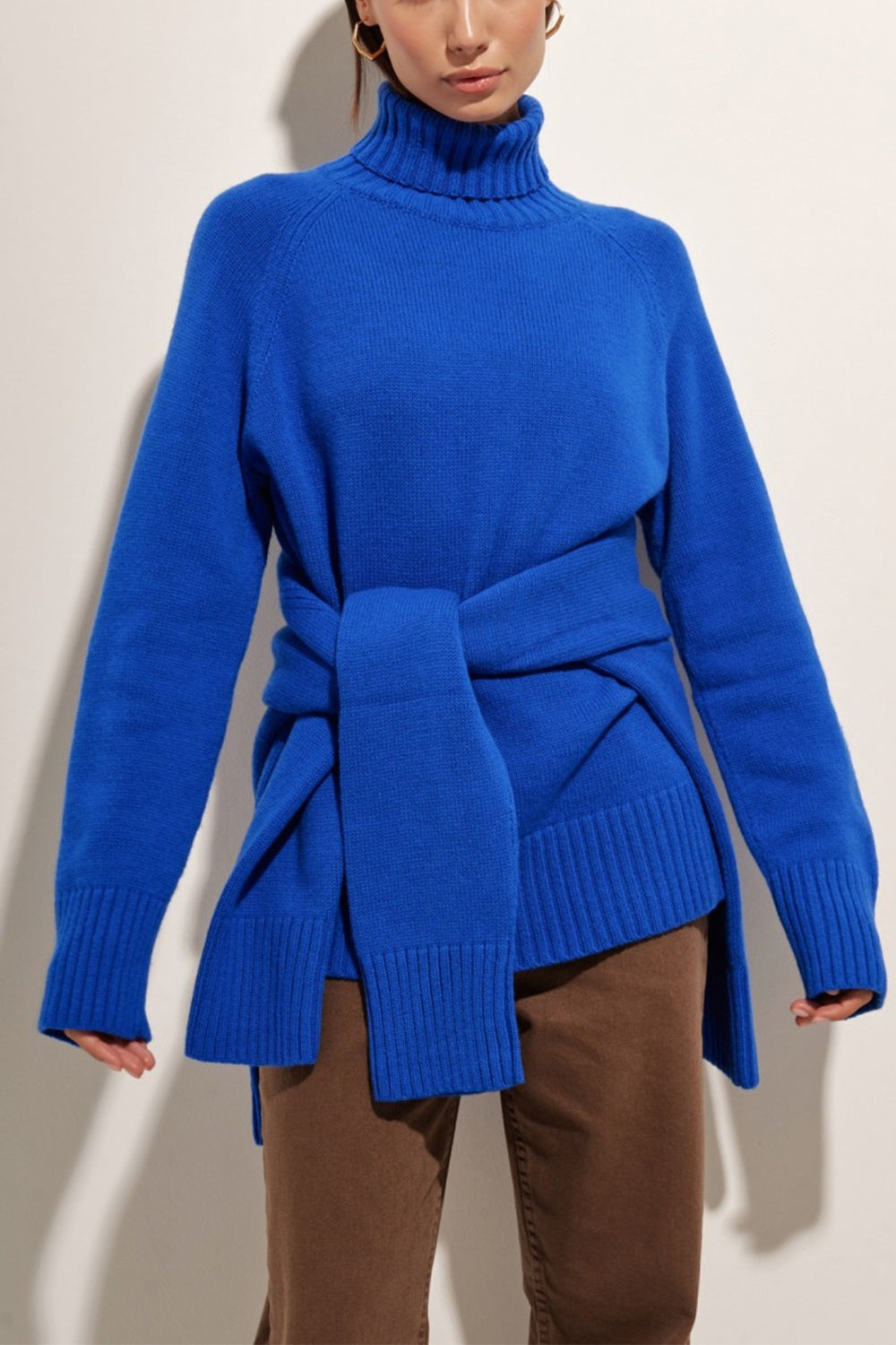 Royal blue cashmere turtleneck sweater with raglan sleeves and a tie waist detail.