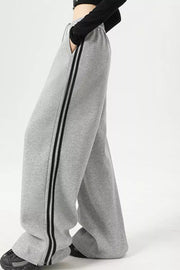 Light gray sweatpants with wide legs and double black side stripes.