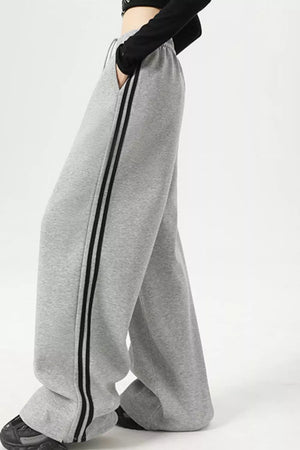 Light gray sweatpants with wide legs and double black side stripes.