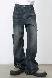 Baggy dark navy denim jeans with distressed knee slits and raw hems.