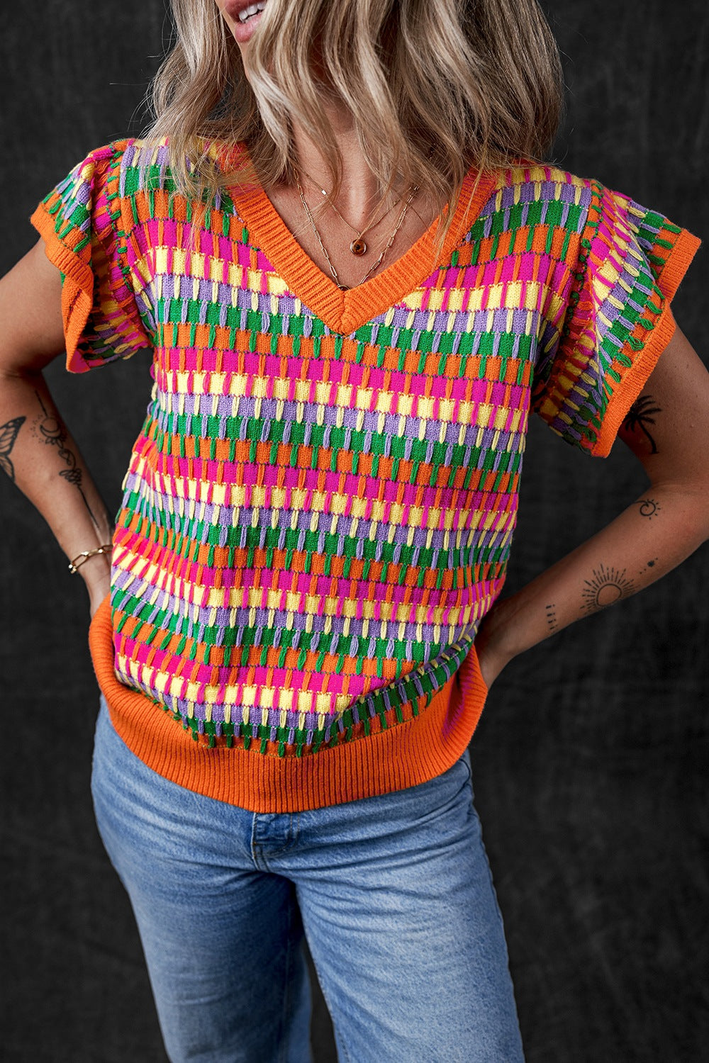Geometric knit v-neck top with flutter sleeves and orange trim.