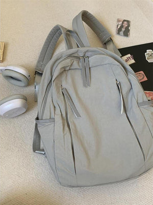 Light gray lightweight nylon backpack with multiple zippered pockets and adjustable straps.