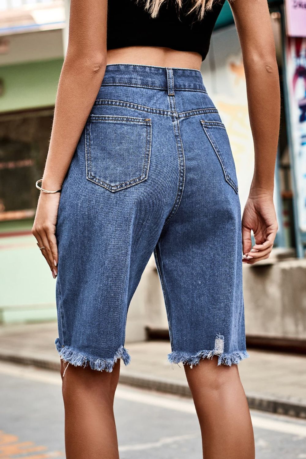 Medium wash denim bermuda shorts with frayed hem and high rise waist.