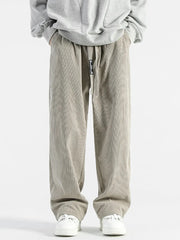 Men's gray corduroy wide-leg sweatpants with drawstring waist and white sneakers.