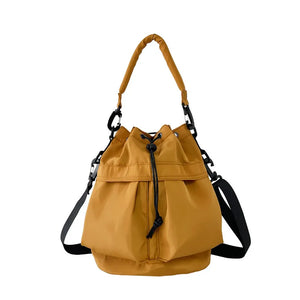 Mustard nylon drawstring bucket bag with top handle and crossbody strap.