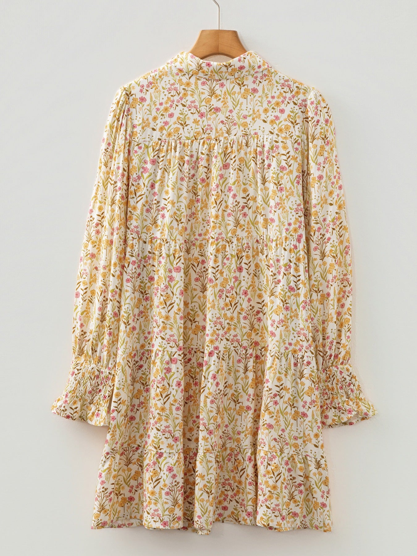 Floral print tiered shirt dress with buttoned collar and smocked cuffs.