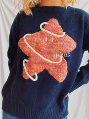Navy knit jumper with textured orange starburst embroidery and white rope detail.