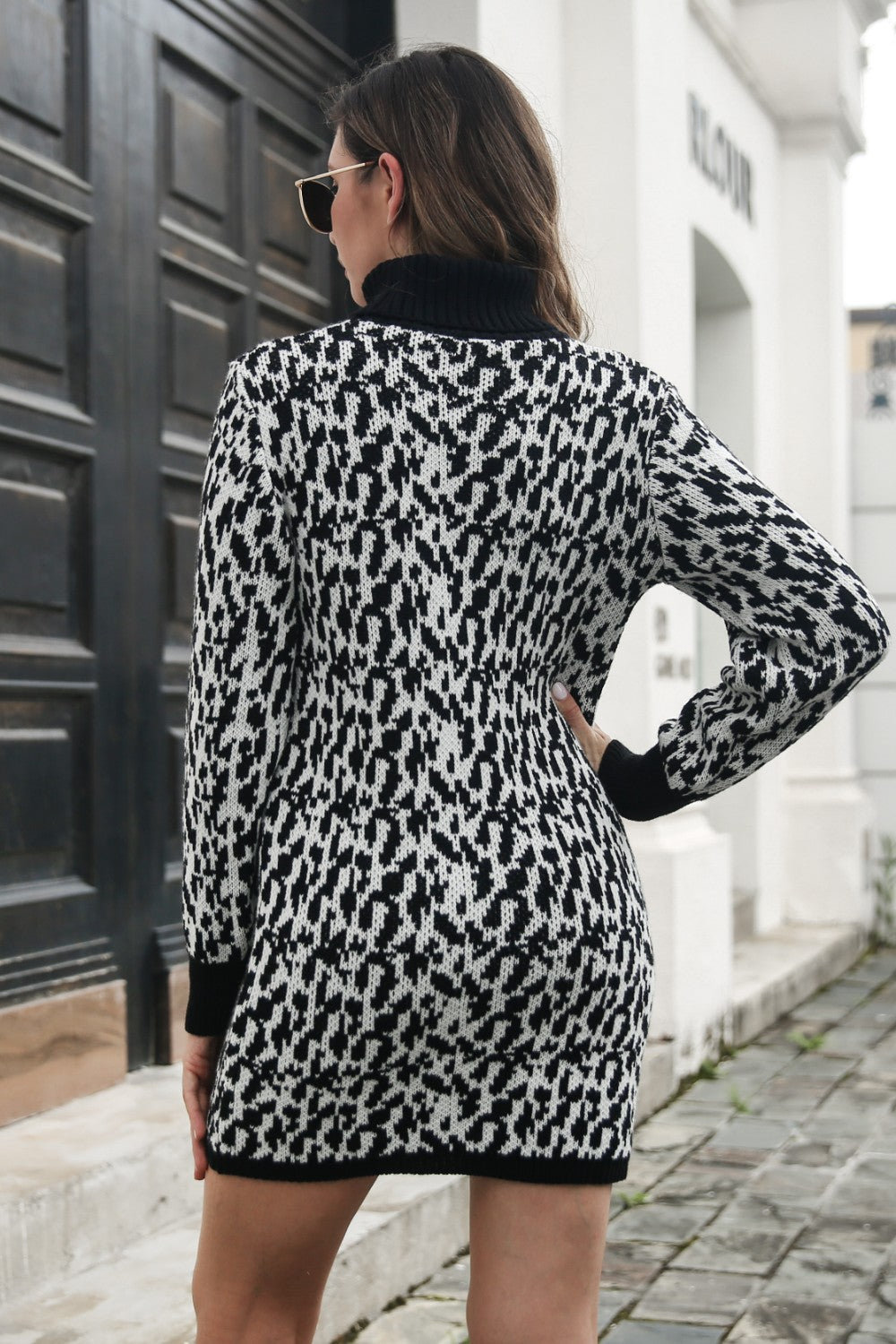 Black houndstooth knit turtleneck mini dress with long sleeves.