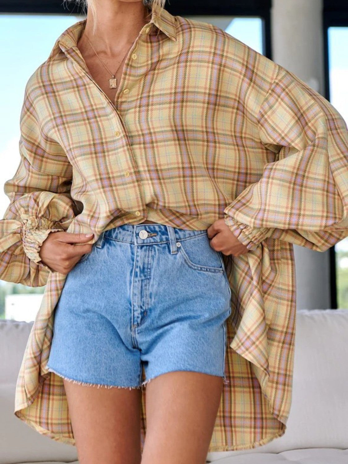 Overshirt in plaid with balloon sleeves and ruffled cuffs, styled with denim shorts.