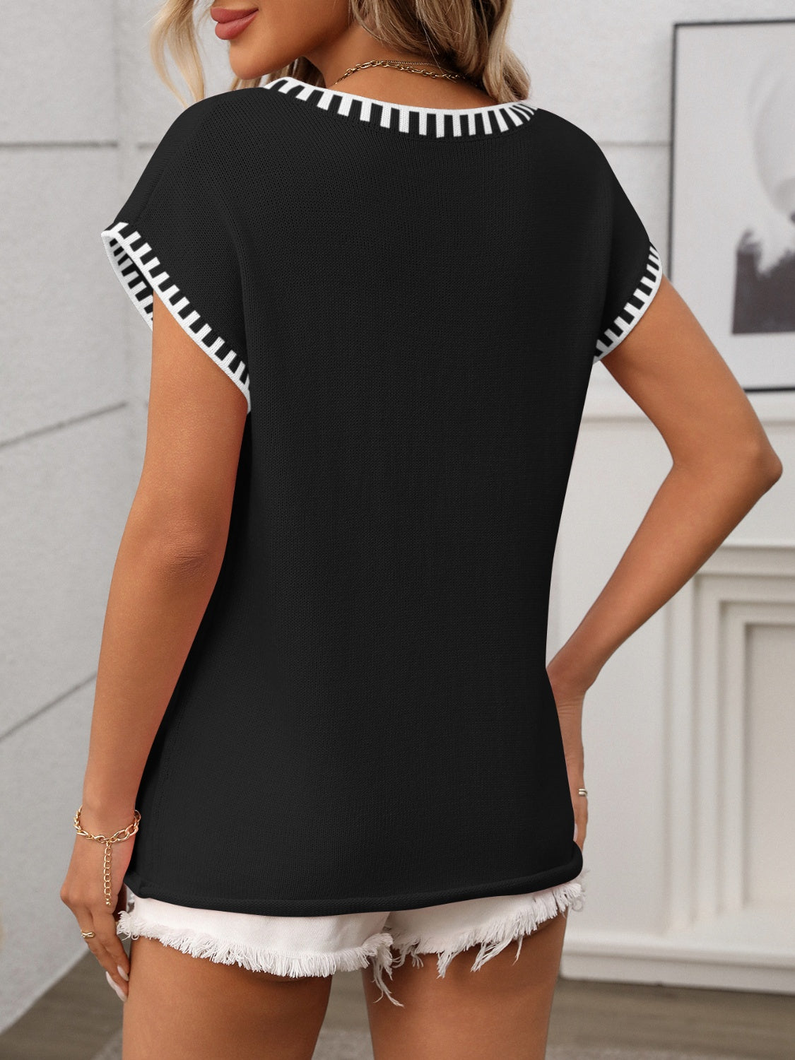 Black knit V-neck top with white contrast trim on neckline and sleeves.