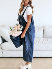 Ripped relaxed fit denim overalls in dark blue, with adjustable straps and distressed details.