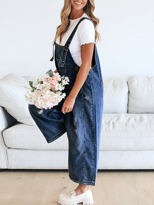 Ripped relaxed fit denim overalls in dark blue, with adjustable straps and distressed details.