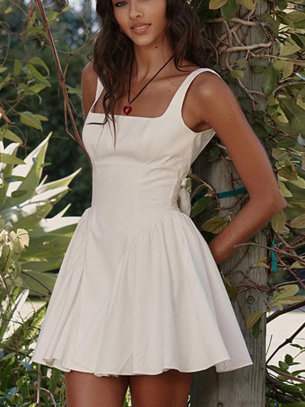 White backless mini dress with square neckline and bow detail.