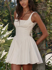 White backless mini dress with square neckline and bow detail.