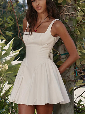 White backless mini dress with square neckline and bow detail.