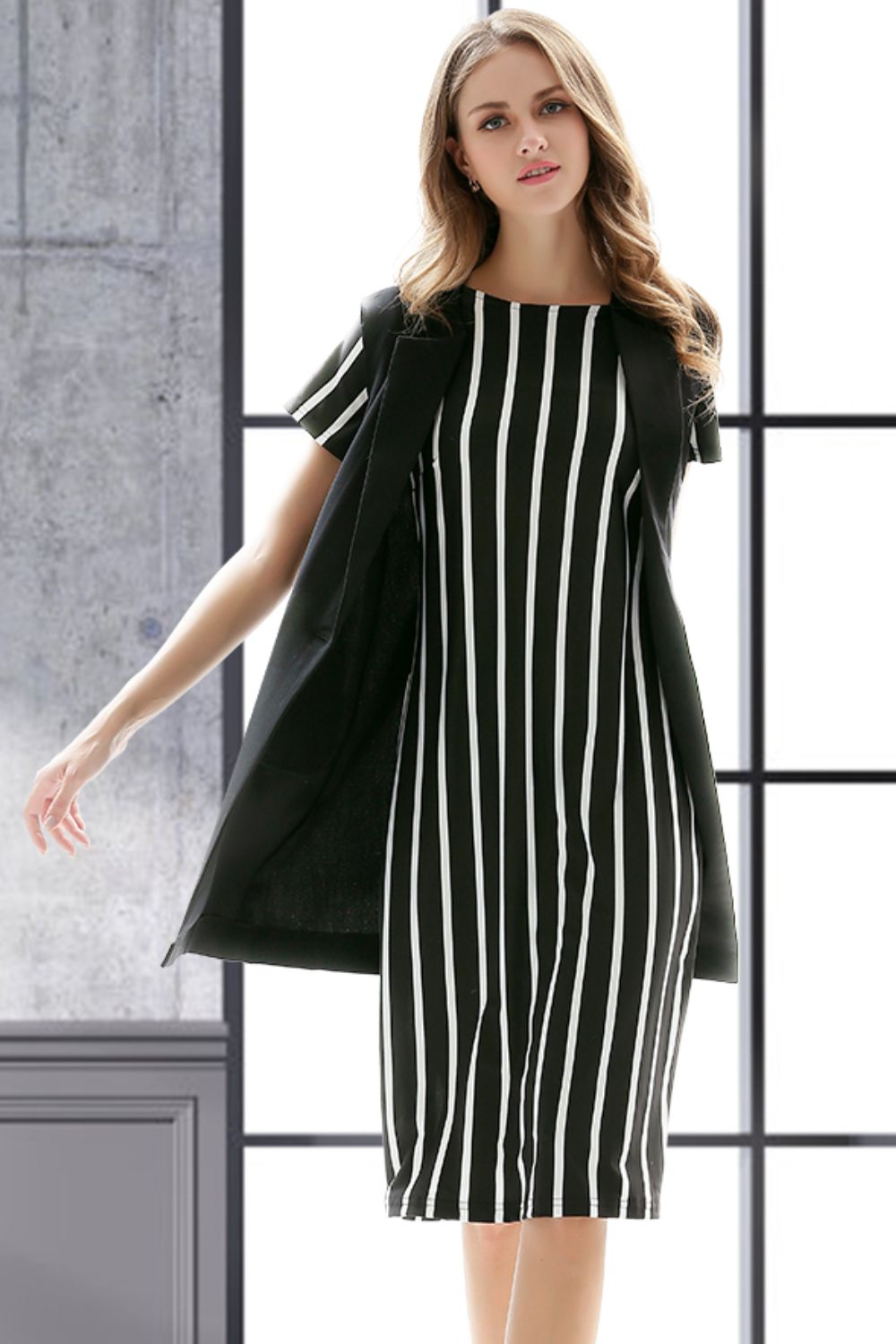 Black tailored sleeveless vest with single button closure over a striped dress.