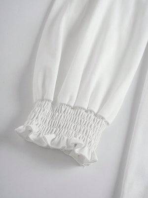 White tunic top with smocked ruffled cuffs and voluminous sleeves.