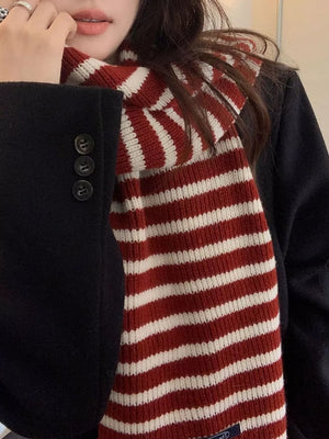 Cozy wool scarf in deep red and white stripes, worn with a black coat.