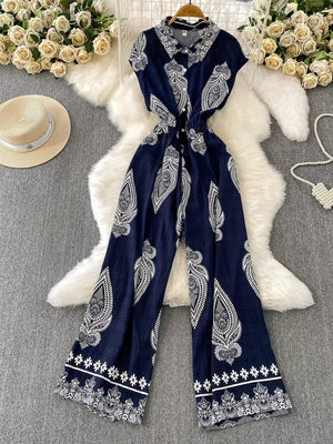 Navy blue wide leg romper with white paisley print, collared, button-down front, short sleeves.