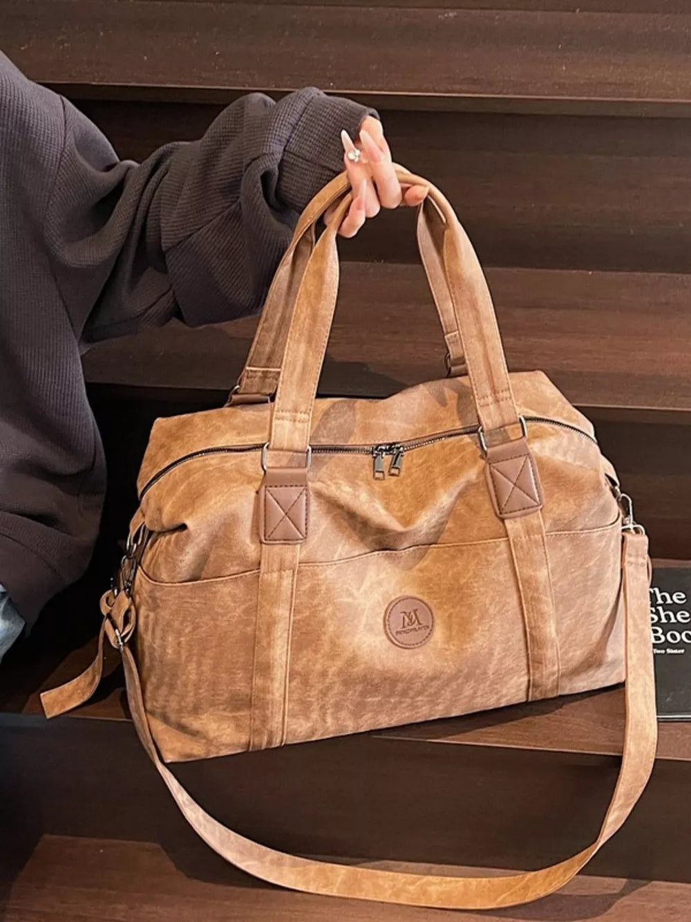 Distressed brown leather travel duffel bag with adjustable strap and dual handles.