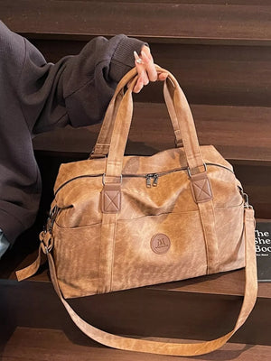 Distressed brown leather travel duffel bag with adjustable strap and dual handles.