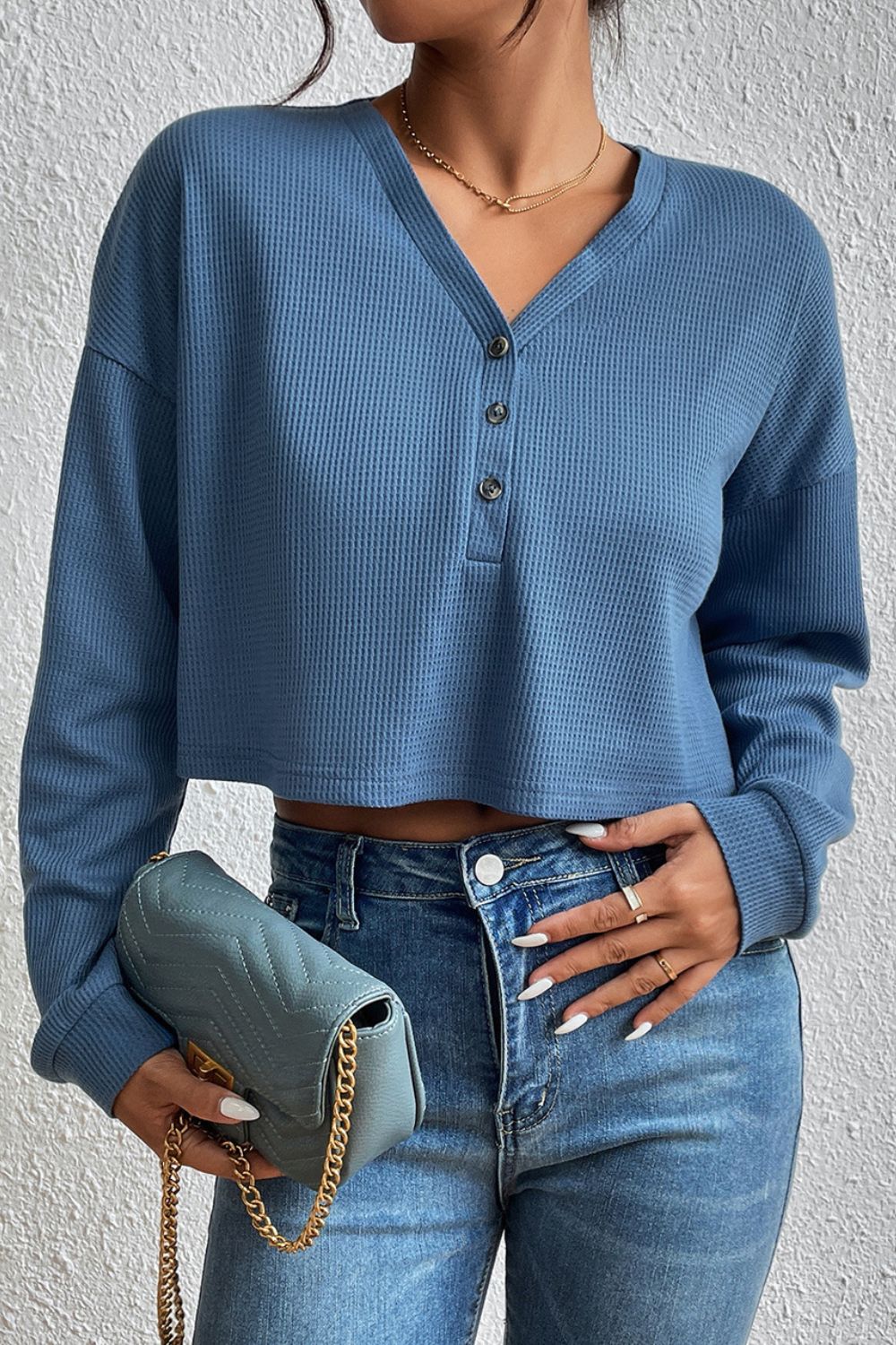 Dusty blue waffle knit henley crop top with button placket and long sleeves.