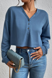 Dusty blue waffle knit henley crop top with button placket and long sleeves.