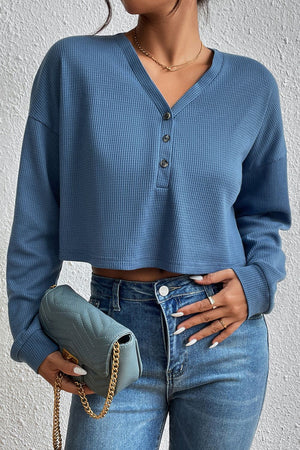 Dusty blue waffle knit henley crop top with button placket and long sleeves.