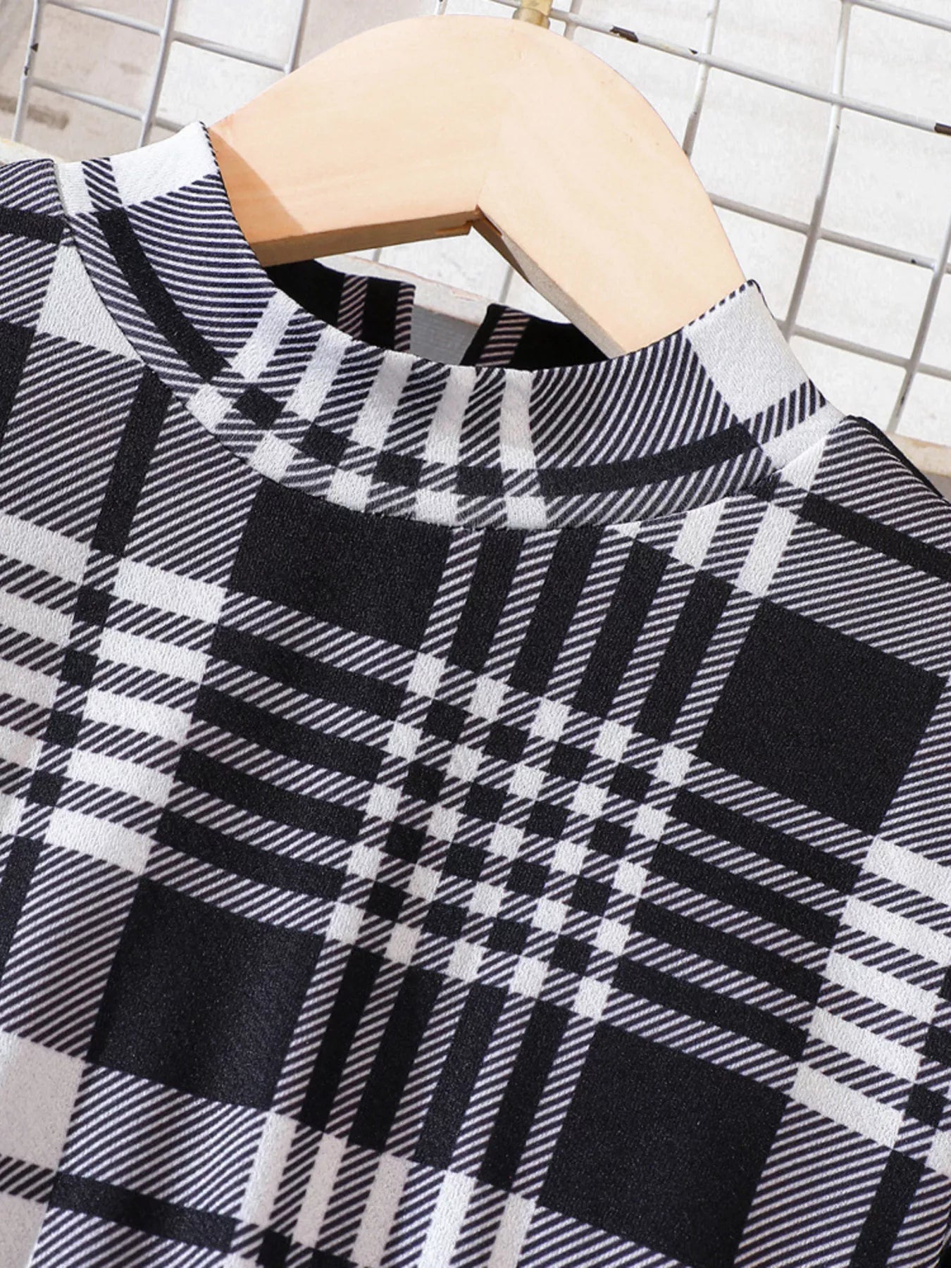 Black and white plaid baby dress with mock neck and long sleeves.