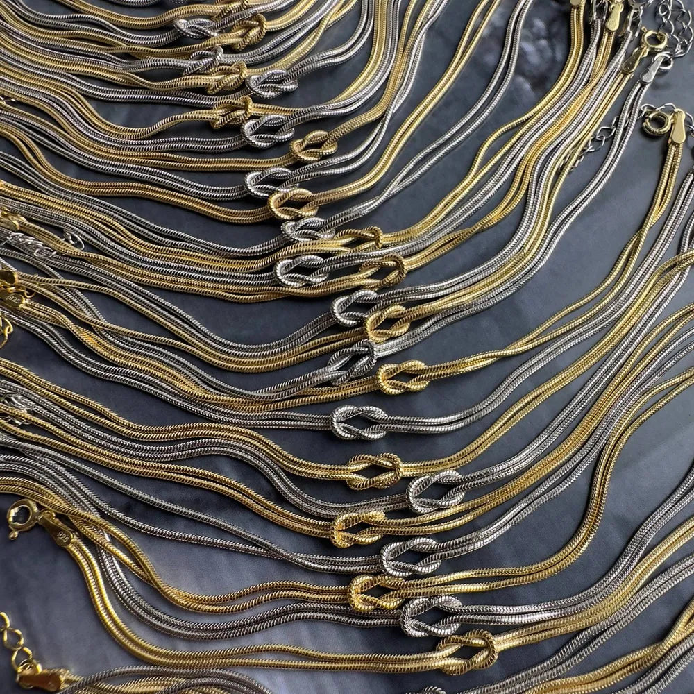 Two-tone serpent knot necklaces in gold and silver montage.