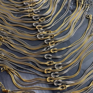 Two-tone serpent knot necklaces in gold and silver montage.